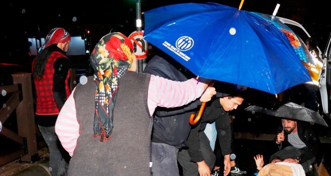 Motosikletten düşen kadını şemsiyelerle yağmurdan korudular